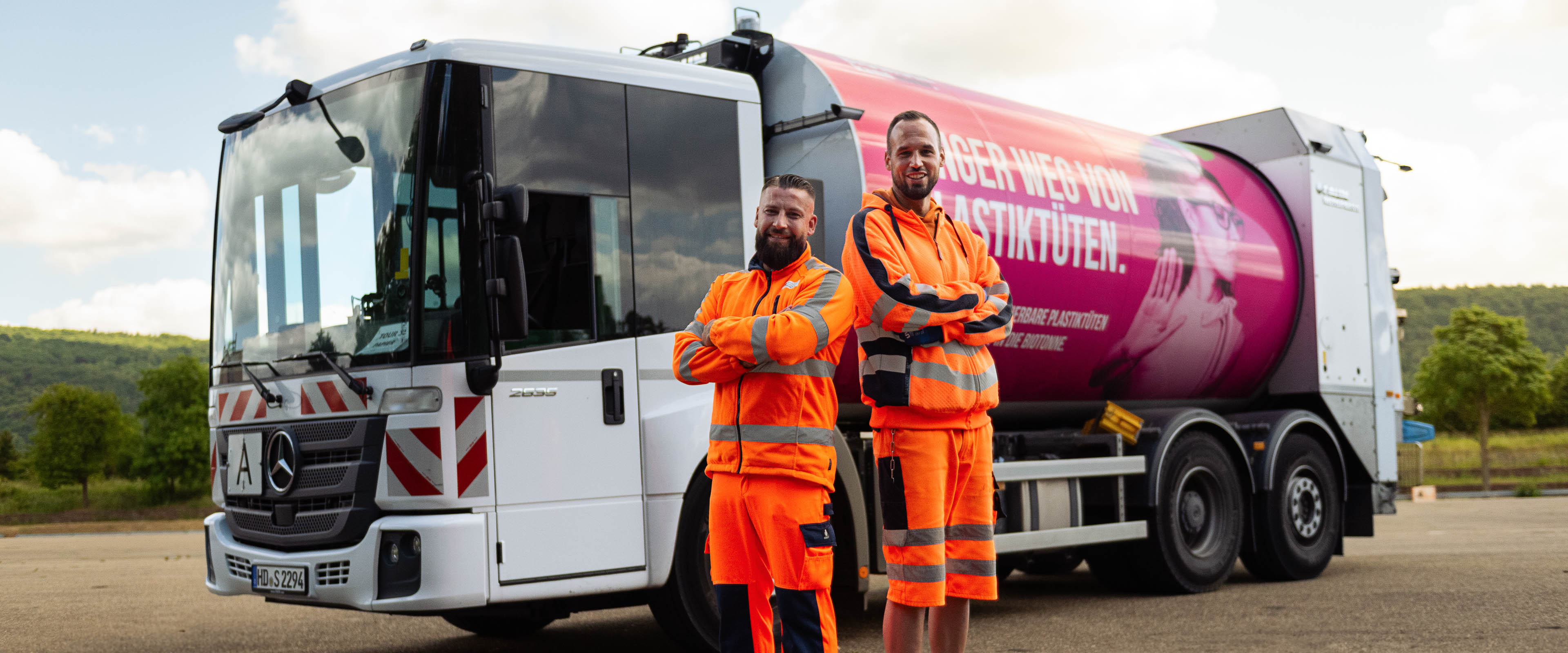 Zwei Müllwerker stehen vor einem Müllfahrzeug
