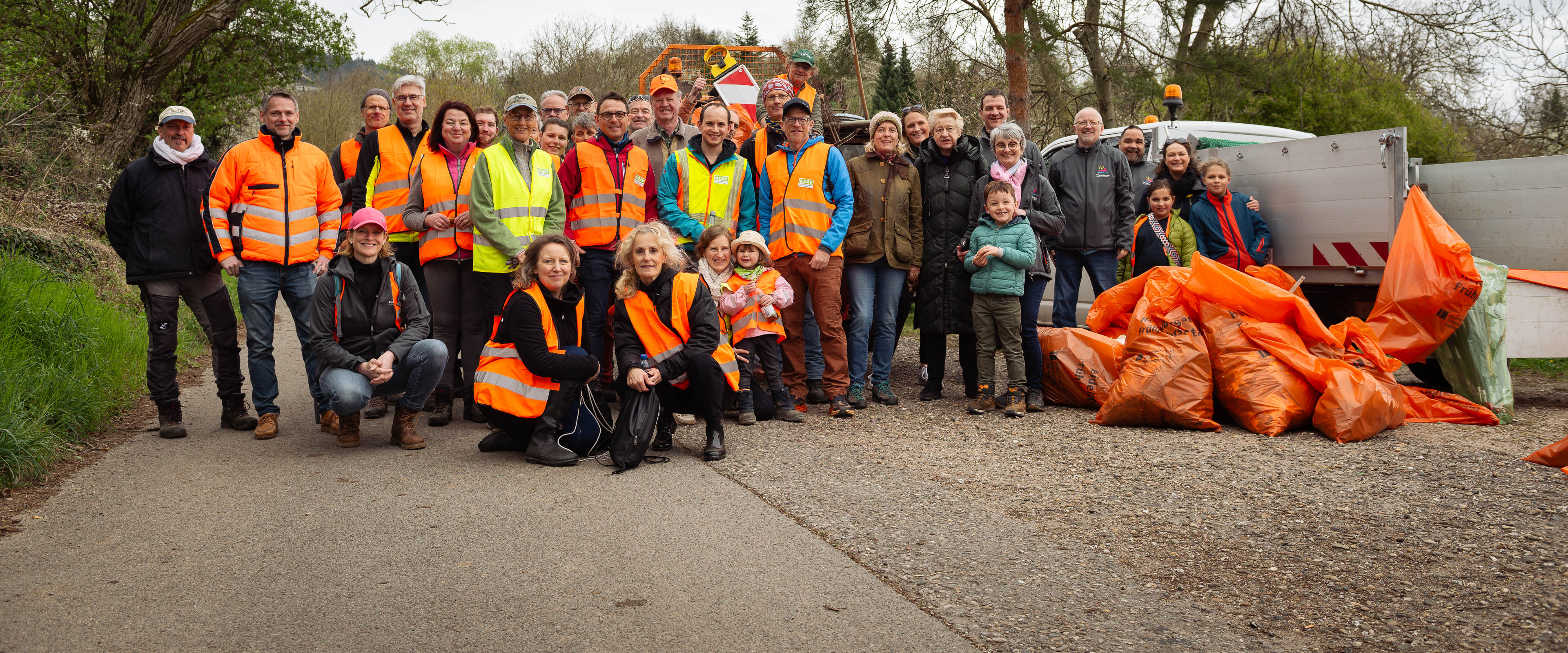 Eine Gruppe von Menschen in orangenen Warnwesten nehmen beim Frühjahrsputz teil.