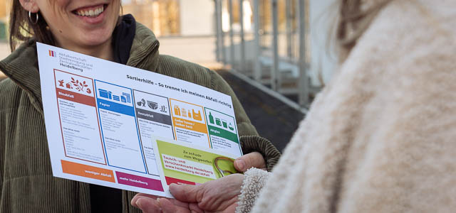 Eine junge Frau überreicht eine Sortierhilfe für Abfall
