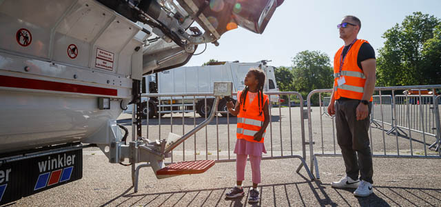 Ein Kind bedient die Schüttung eines Abfallsammelfahrzeugs