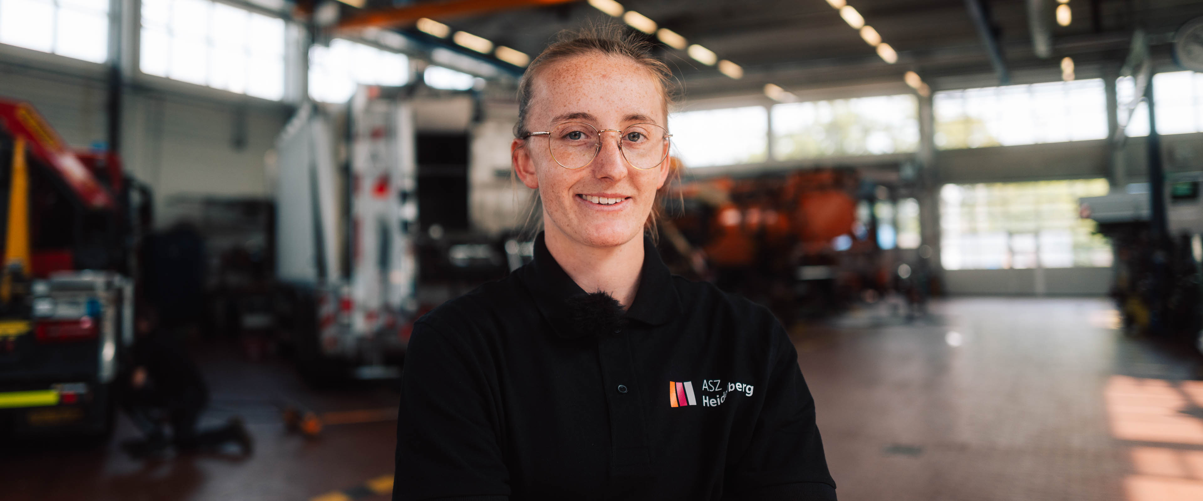 Eine junge Frau steht in der KFZ-Werkstatt