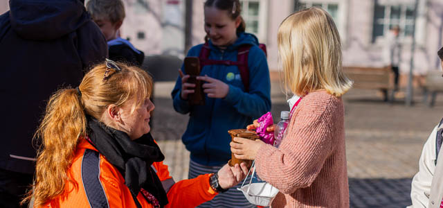Eine junge Frau überreicht einem Kind ein Geschenk